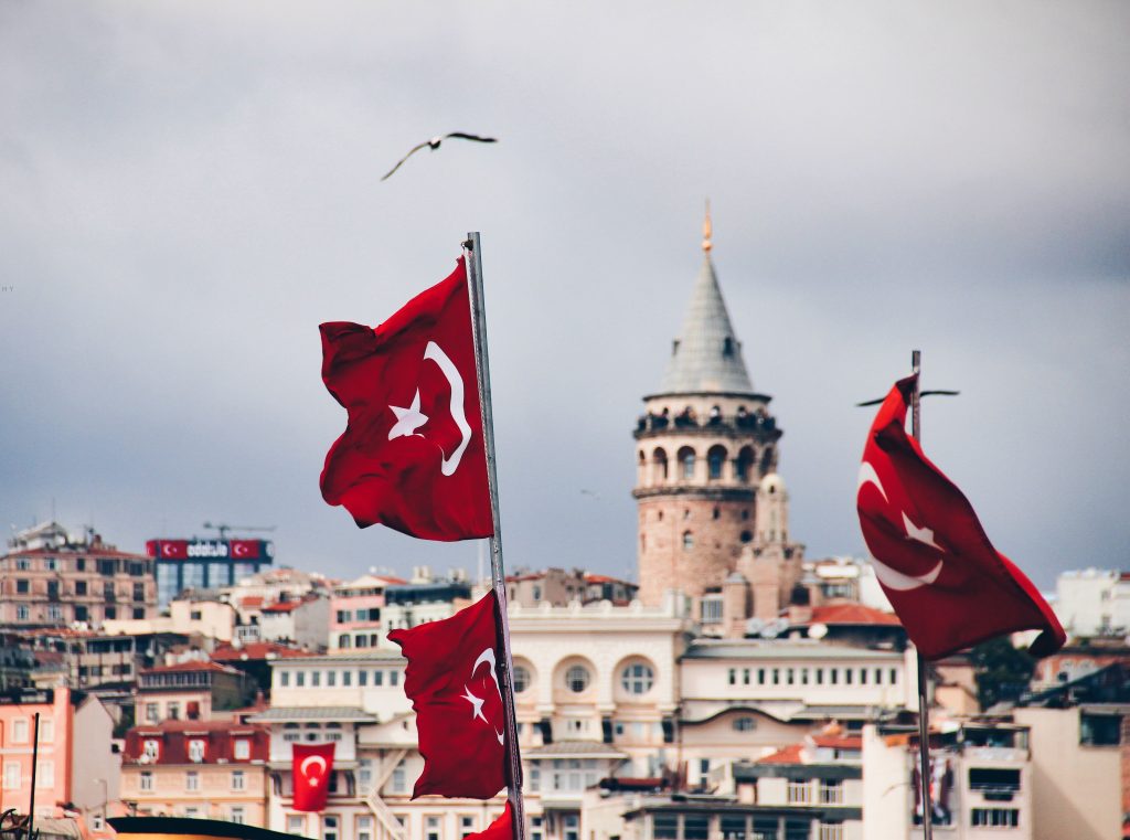 Turkish flags waving in front of Galata Tower in Istanbul, symbolizing national pride and identity.